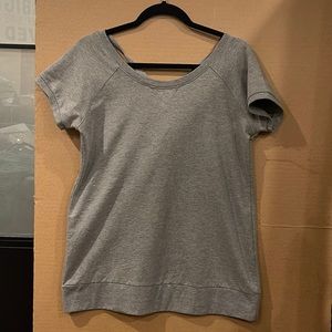 Nene leakes grey short sleeved sweatshirt with cross straps in the back.